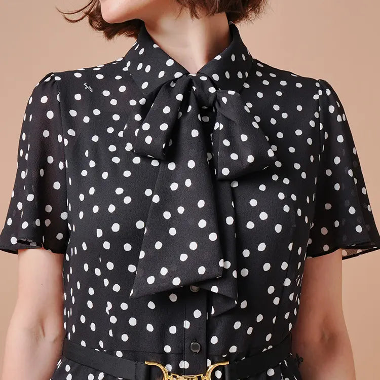 An elegant shirt dress featuring a dramatic bow tie and a monochrome design.