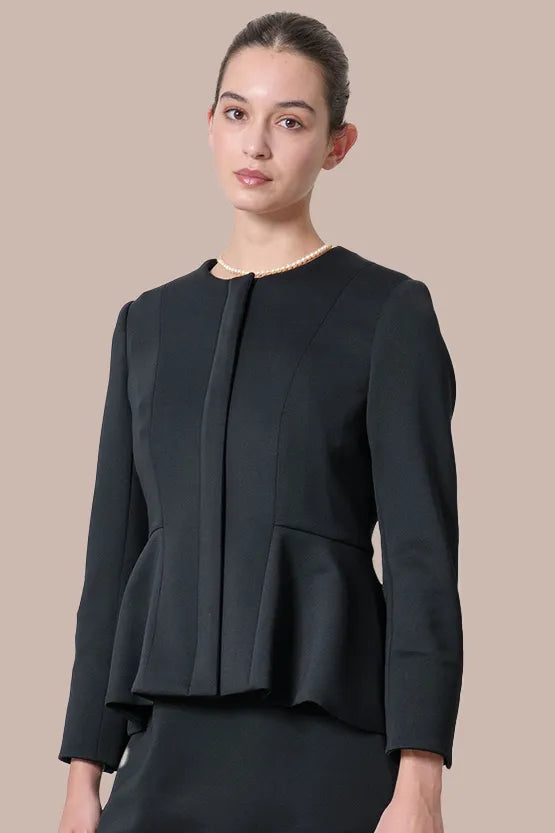 A woman wears a black Space Material Peplum Jacket with a structured silhouette and subtle sheen.