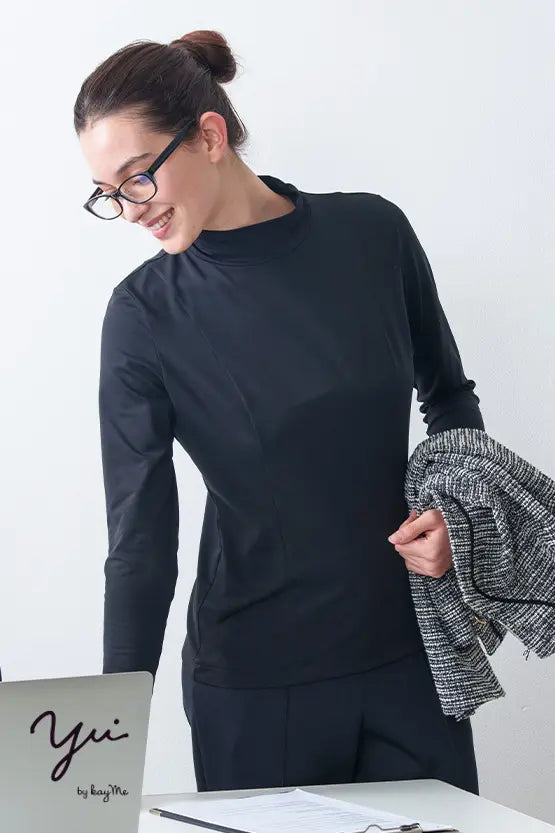 Woman in a black Wellness Tech high neck top, showing side view of the athletic shirt's smooth fabric and high neckline.