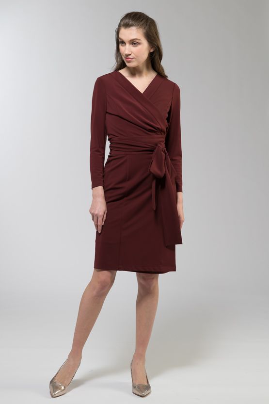 A woman models a flowy, floral print wrap dress with a V-neckline and tie waist.