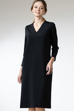 Woman wearing a long-sleeve black V-neck dress