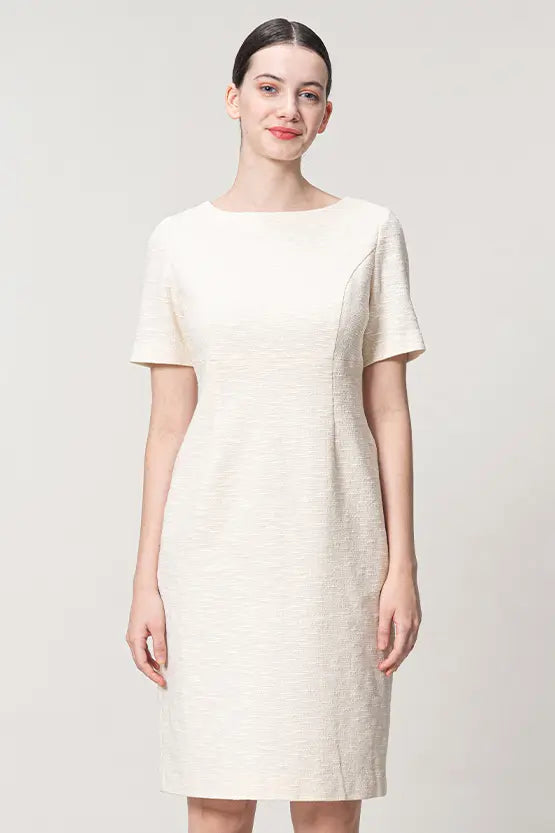 A woman models the Stretch Tweed: Essential Dress, a knee-length navy blue tweed sheath dress with a crew neckline.