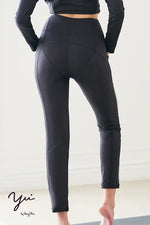 Woman wearing black Wellness Tech: Legging Pants, showcasing their comfortable fit and smooth texture.