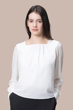 A woman models the Stretch Chiffon: Round Neck Top in a soft pastel color, highlighting its elegant drape and neckline.